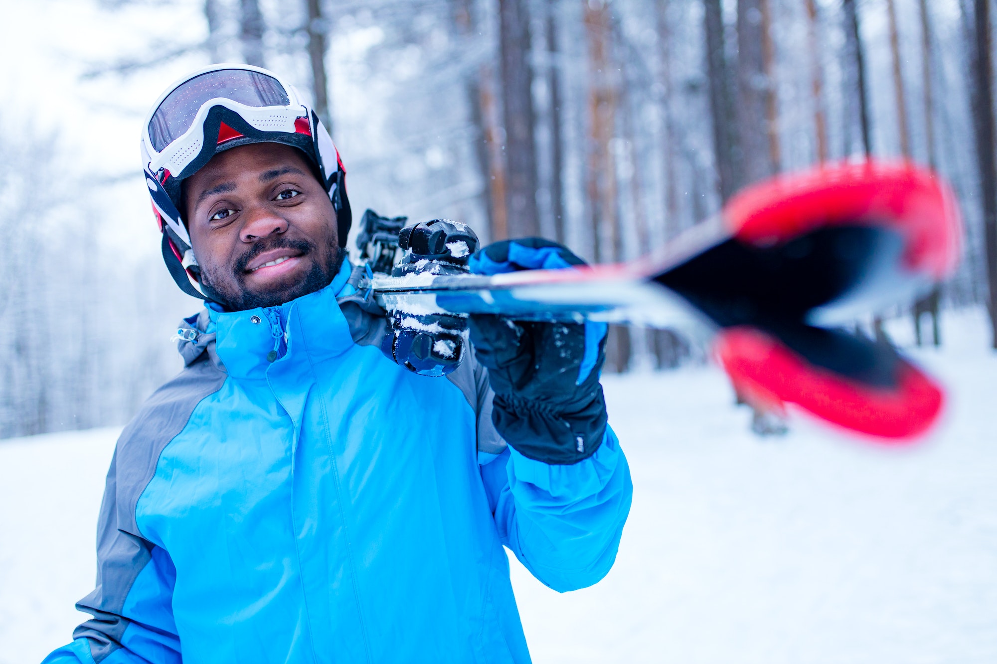 afro american man in blue jacket run ski outdoors in freeze forest